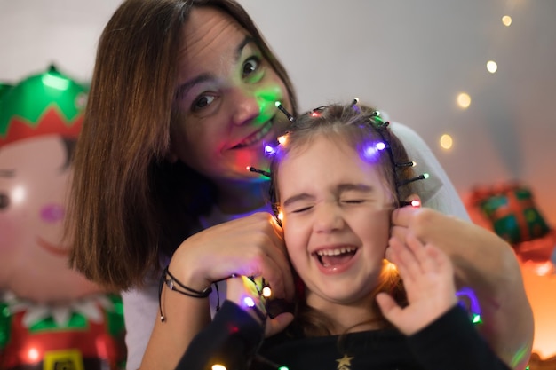 Mãe e filha se divertem brincando com luzes de natal