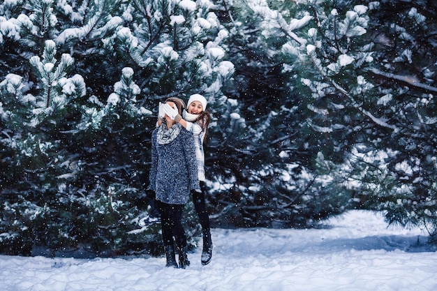 Mãe e filha se divertem brincando na floresta de inverno