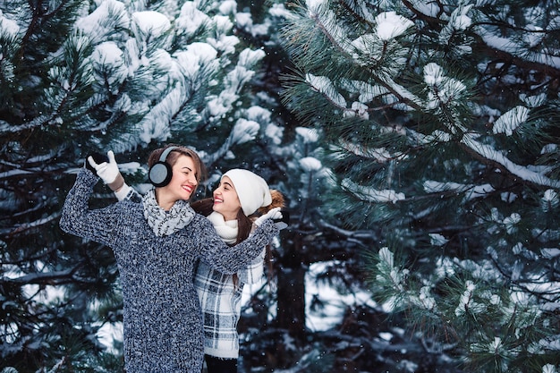 Mãe e filha se divertem brincando na floresta de inverno