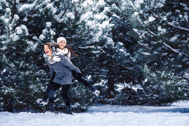 Mãe e filha se divertem brincando na floresta de inverno.