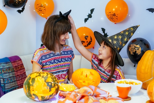 Mãe e filha se divertem limpando o interior da abóbora para fazer jack o lantern para o halloween