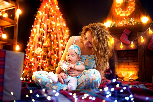 Mãe e filha se divertindo brincando juntos perto da árvore de Natal na sala decorada