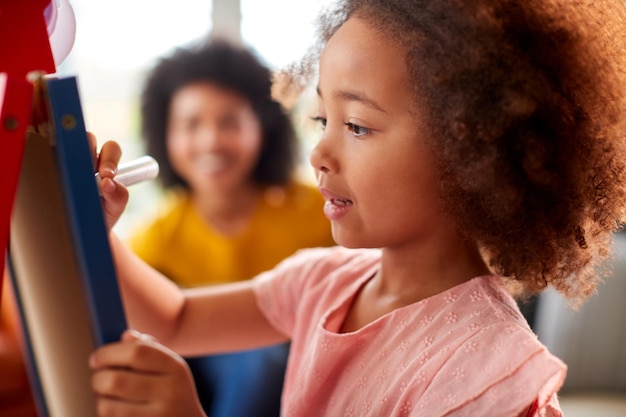 Foto mãe e filha se divertindo desenhando no quadro branco em casa juntos