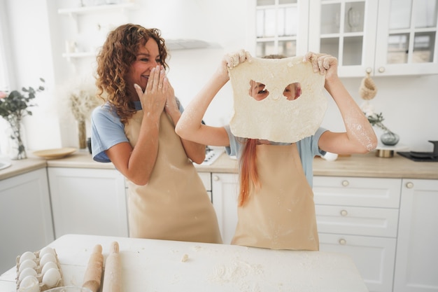 Mãe e filha se divertindo enquanto cozinham massa na cozinha