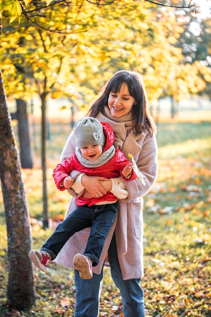 Mãe e filha se divertindo no parque outono entre as folhas que caem. estilo de vida ativo