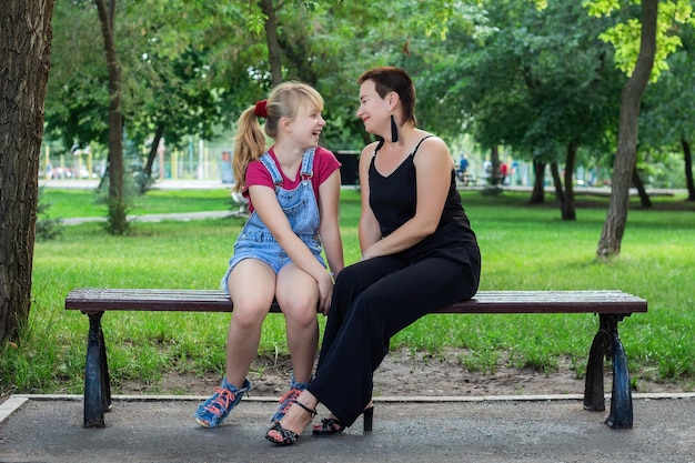 Mãe e filha sentadas em um banco no parque