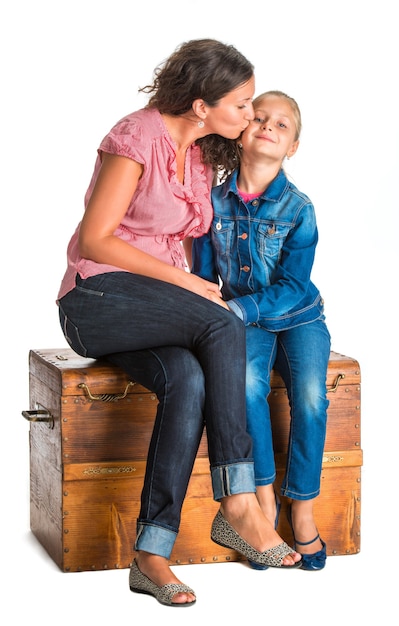 Mãe e filha sentadas em um baú de madeira