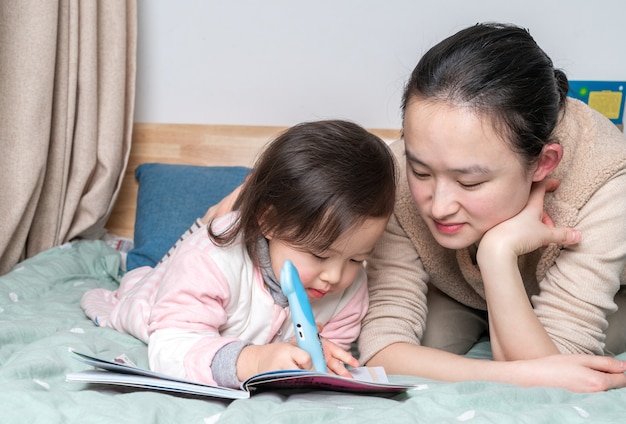 Mãe e filha sentadas na cama lendo juntas