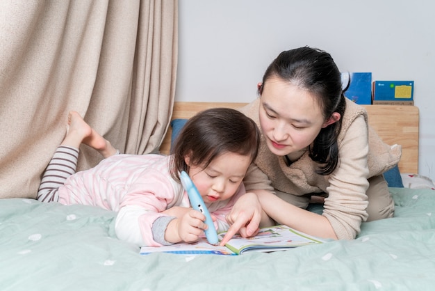 Mãe e filha sentadas na cama lendo juntas