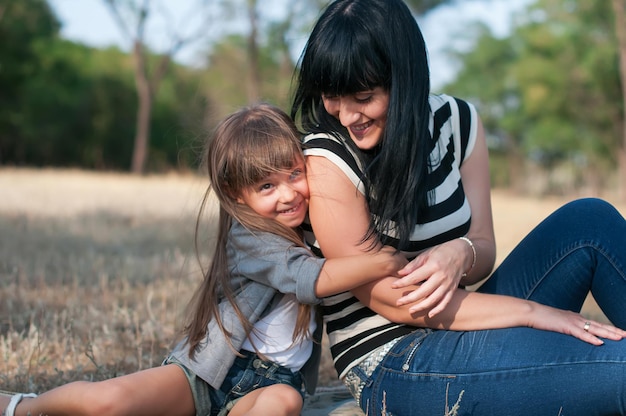 Mãe e filha sentadas no parque na grama