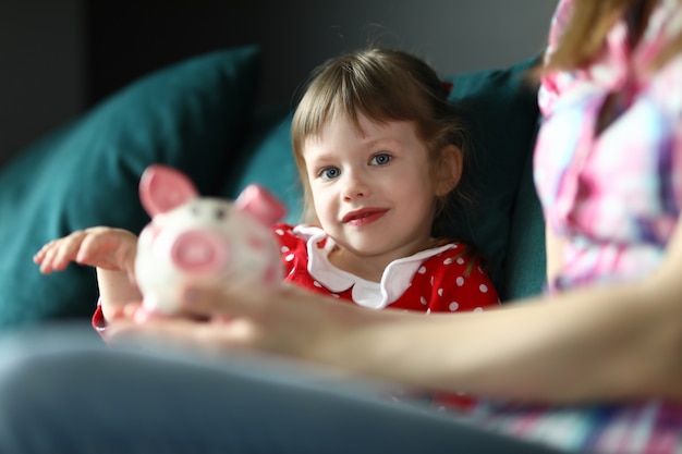 Mãe e filha sentar em casa no sofá com mealheiro