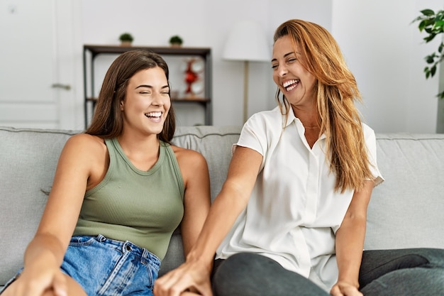 Mãe e filha sorrindo confiantes sentadas no sofá em casa