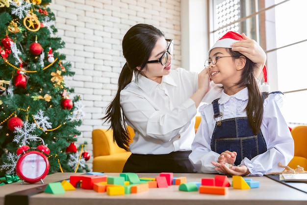 Mãe e filha sorrindo e brincando de brinquedo na época do Natal.