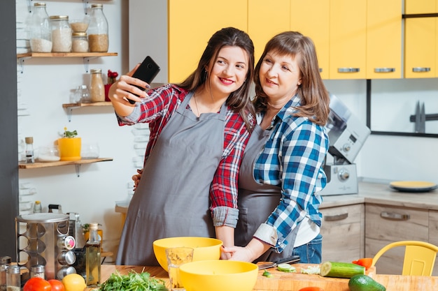 Mãe e filha sorrindo e posando na cozinha
