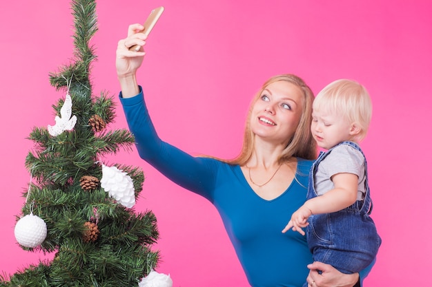 Mãe e filha tirando uma selfie perto da árvore de natal