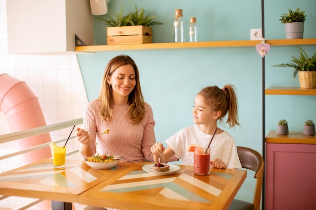 Mãe e filha tomando café da manhã com sucos frescos no café