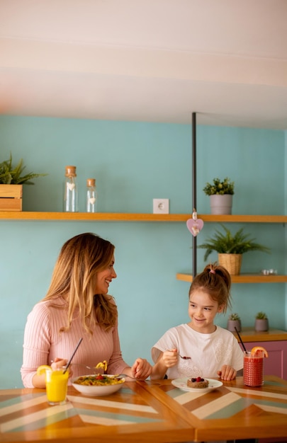 Mãe e filha tomando café da manhã com sucos frescos no café