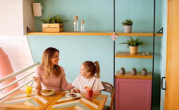 Mãe e filha tomando café da manhã com sucos frescos no café