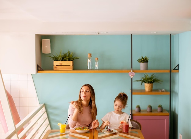 Mãe e filha tomando café da manhã com sucos frescos no café