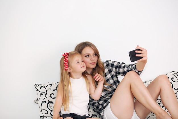 Mãe e filha tomando selfie enquanto descansava na cama em casa