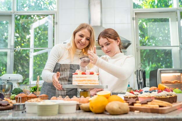 Mãe e filha trabalhando juntas felizmente para fazer doces nas férias