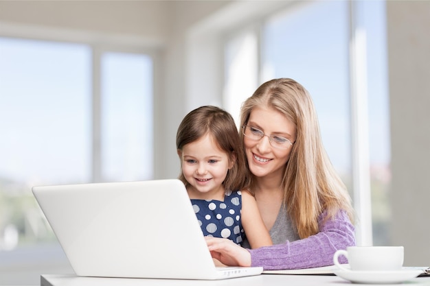 Mãe e filha usando laptop em casa