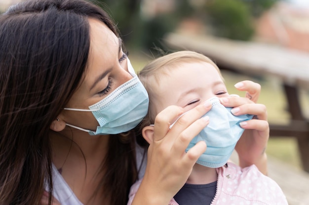 Mãe e filha usando máscara facial protetora ao ar livre