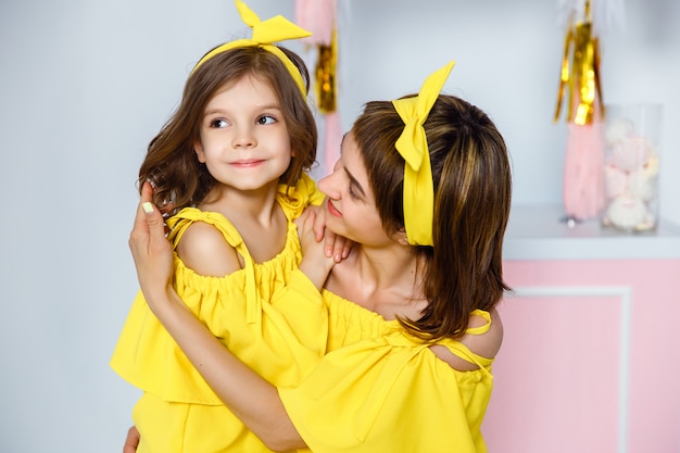 Mãe e filha usando o mesmo vestido amarelo.