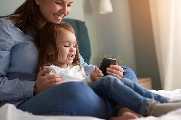 Mãe e filha usando smartphone juntos
