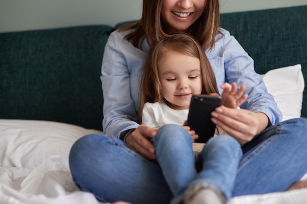 Mãe e filha usando smartphone juntos