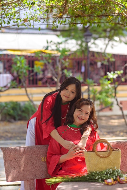 Mãe e filha vietnamitas felizes em vestido vermelho ao dai no parque ao ar livre