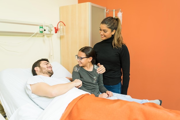 Mãe e filha visitando o pai doente durante o tratamento no hospital