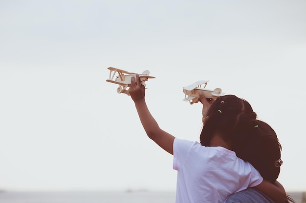 Foto mãe e filha voando avião de brinquedo contra o céu claro