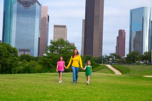 Mãe e filhas andando de mãos dadas no horizonte da cidade