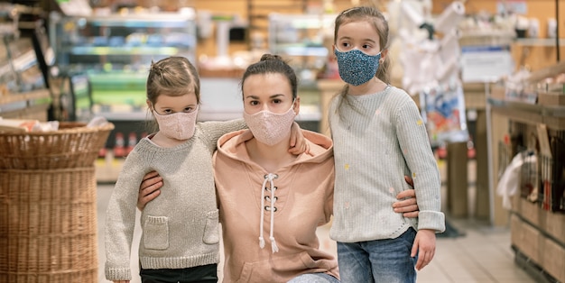 Mãe e filhas compram máscaras na loja durante a quarentena devido à pandemia de coronavírus.