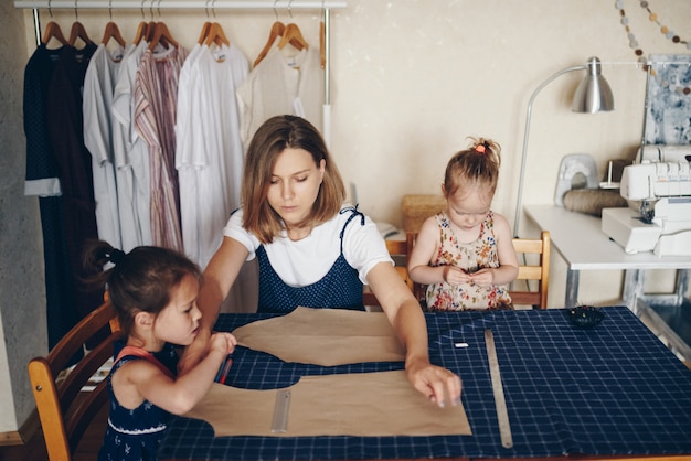Mãe e filhas costuram roupas juntos. Vestido padrão.
