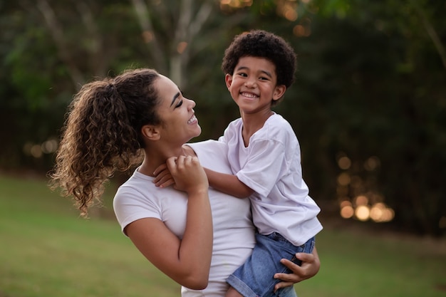 Mãe e filho afro no parque sorrindo para a câmera