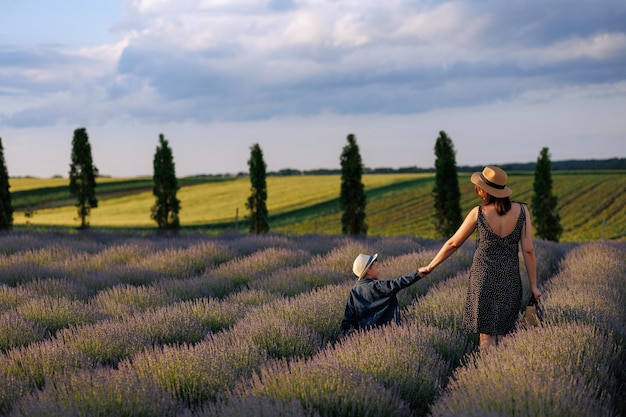 Mãe e filho andam de mãos dadas em um belo campo de paisagem com lavanda