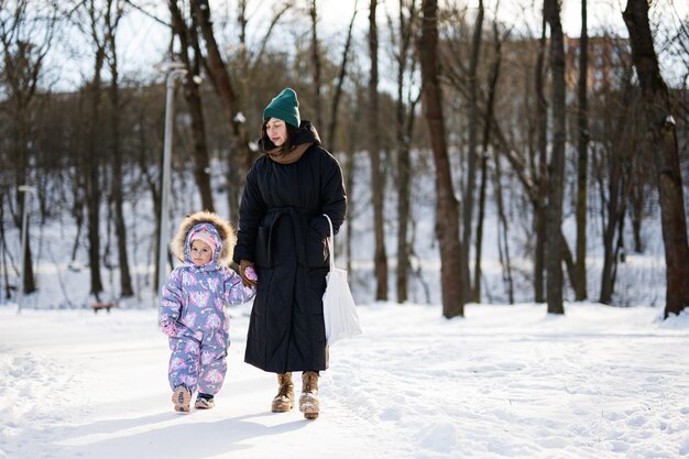 Mãe e filho andando em um dia ensolarado de inverno gelado no parque