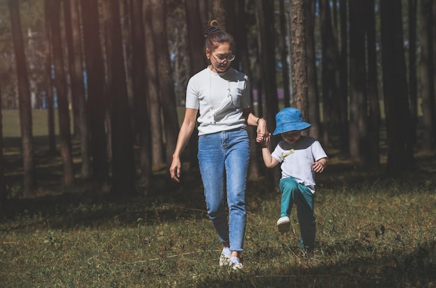 Mãe e filho asiáticos no jardim da natureza com iluminação solar ao ar livre.