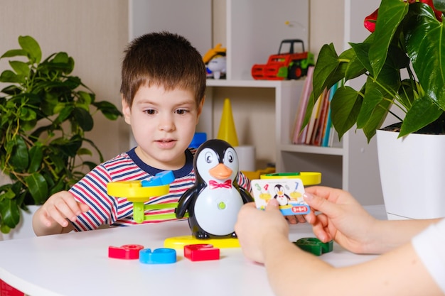 Mãe e filho brincam com números, pesam um pinguim em uma balança de brinquedo.