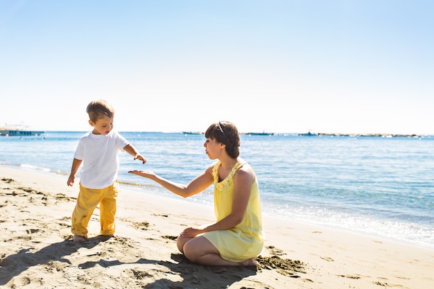 Mãe e filho brincando na praia tropical de verão