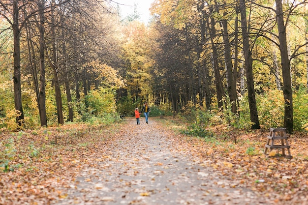 Mãe e filho caminhando no parque outono e apreciando a bela natureza do outono. Temporada, conceito de mãe solteira e filhos.