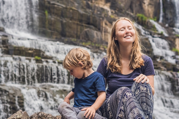 Mãe e filho caminhantes, turistas na superfície da incrível cachoeira Pongour é famosa e a mais bonita do outono no Vietnã