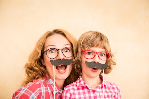 Foto mãe e filho com bigode falso família feliz jogando em casa