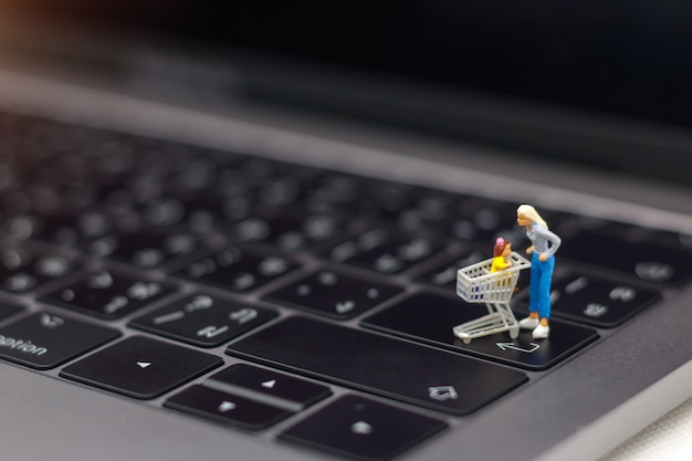 Mãe e filho com cartão de compras em pé no teclado do laptop.