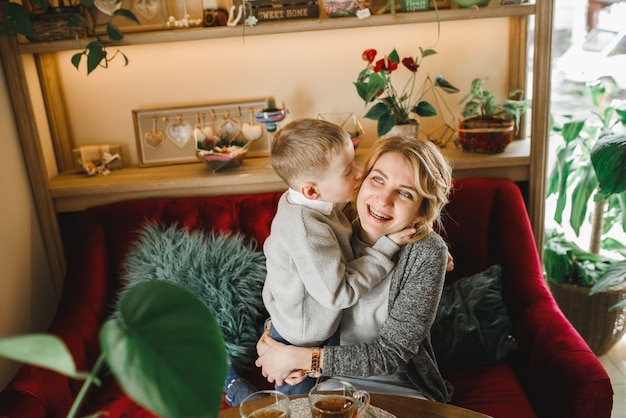 Mãe e filho com flores em caffe. filho dá flores para a mãe. família fofa. dia internacional da mulher, 8 de março comemorando