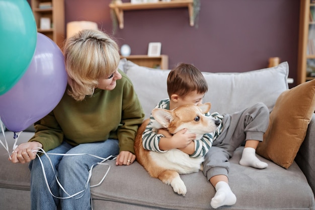 Mãe e filho com síndrome de down abraçados com cachorro sentados juntos no sofá