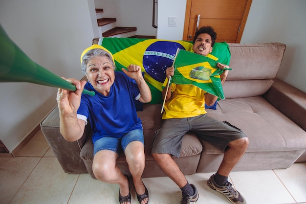 Mãe e filho comemorando a Copa na sala assistindo TV torcendo pelo Brasil