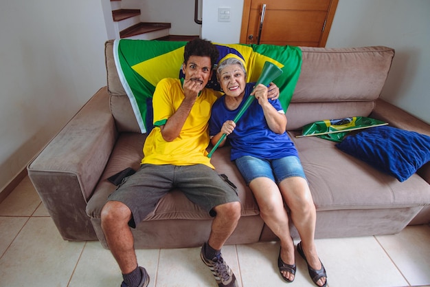 Mãe e filho comemorando a Copa na sala assistindo TV torcendo pelo Brasil